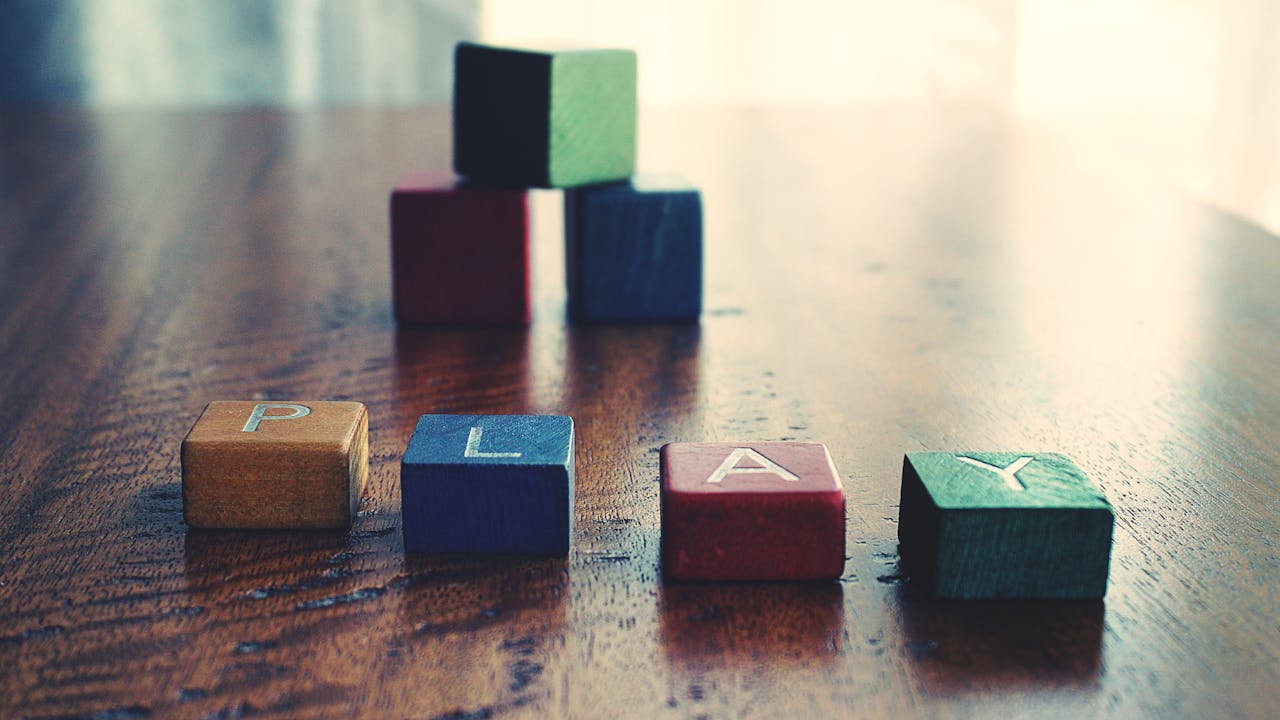 Home A vibrant still life of wooden alphabet blocks spelling 'PLAY' on a wooden surface.
