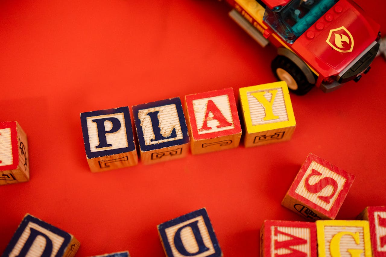 Crafting Captivating Headlines: Your awesome post title goes here Wooden alphabet blocks spelling 'PLAY' beside a toy car on a red background.
