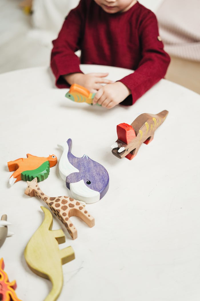 About A child playing with colorful wooden animal toys on a table indoors, fostering creativity and learning.